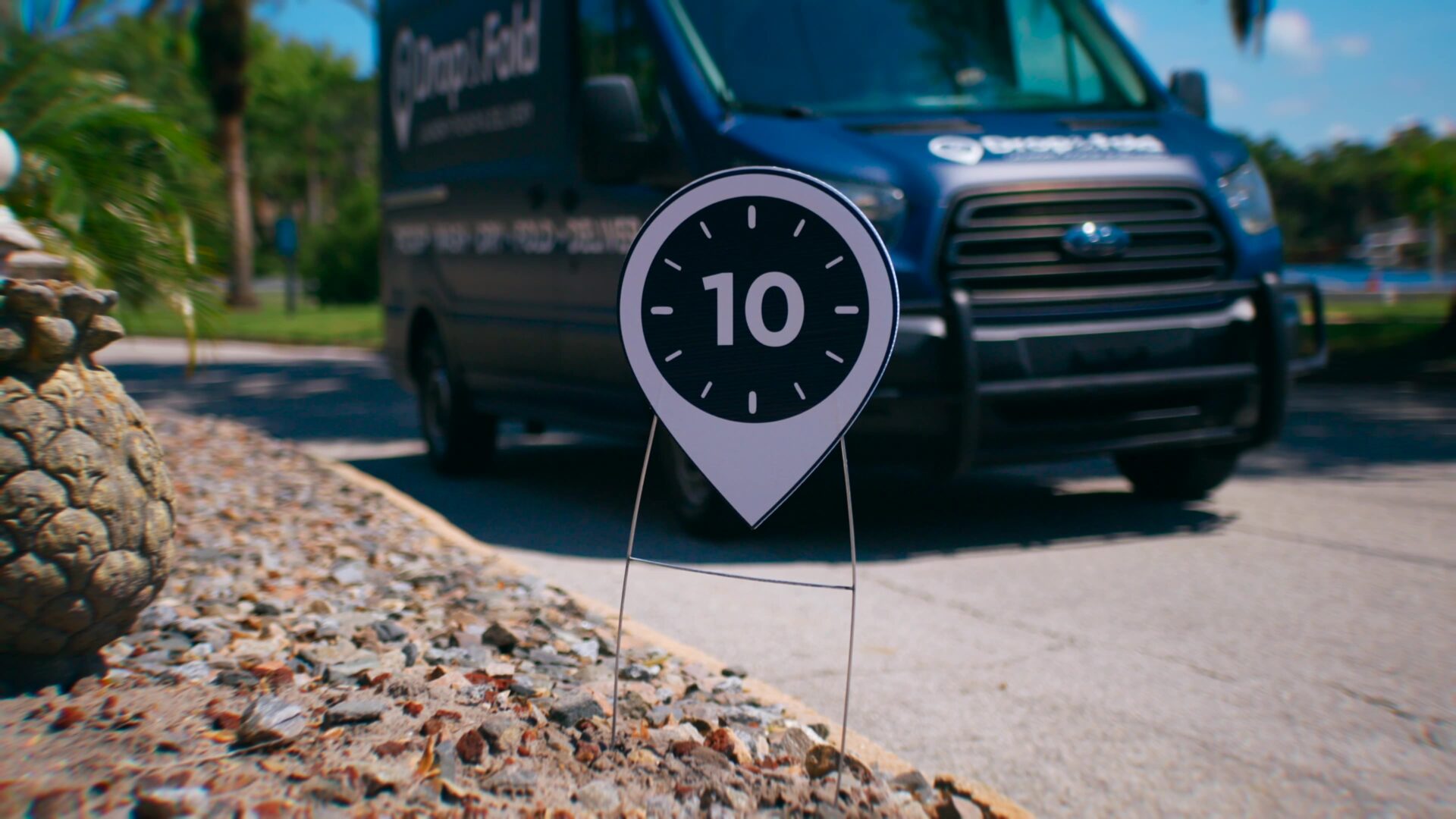 A Drop & Fold Laundry van beside a sign marking the ten hours a month the service gives back